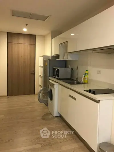 Modern kitchen with sleek white cabinets and built-in appliances in a cozy apartment.
