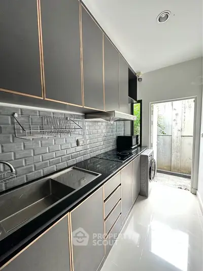 Modern kitchen with sleek cabinetry and open layout, featuring a washing machine and ample natural light.