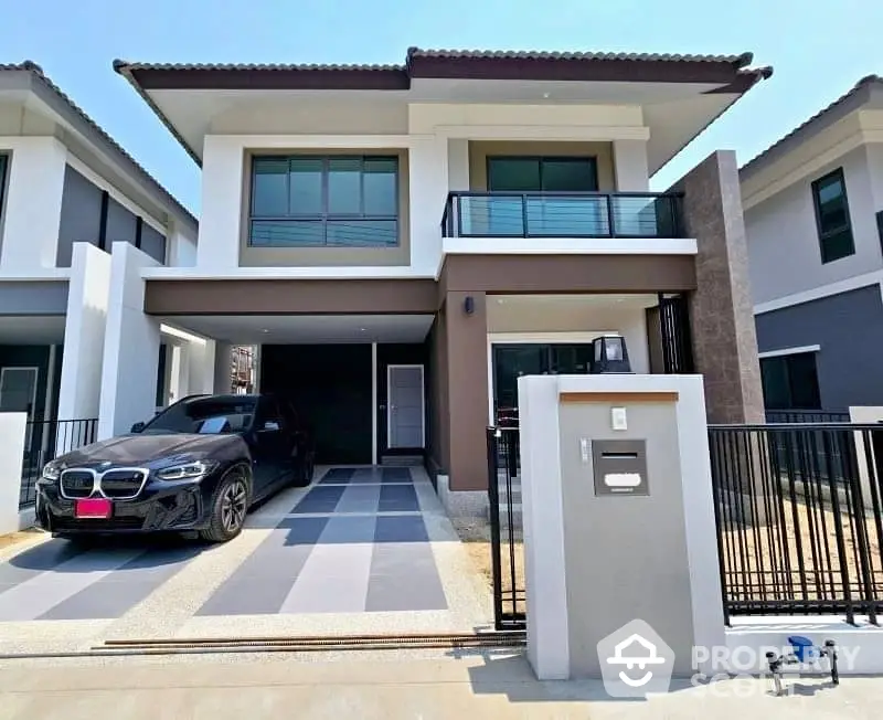 Modern two-story house with driveway and sleek car parked in front, featuring contemporary design and large windows.