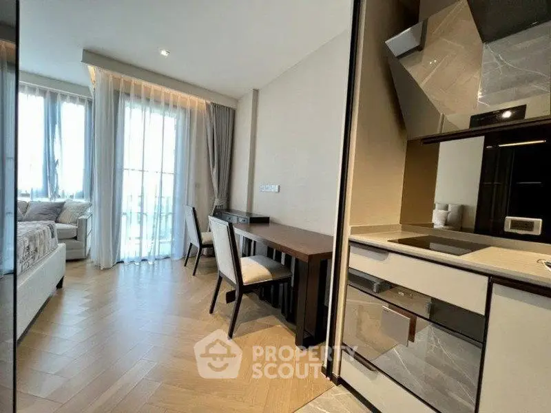 Modern apartment interior with open kitchen and cozy living area, featuring elegant furnishings and natural light.