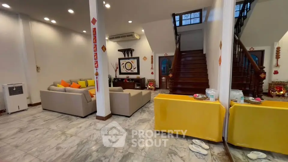 Spacious living room with modern decor and elegant staircase, perfect for family gatherings.