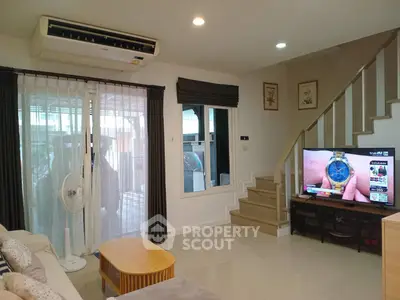 Cozy living room with modern decor and staircase, featuring a TV and air conditioning.