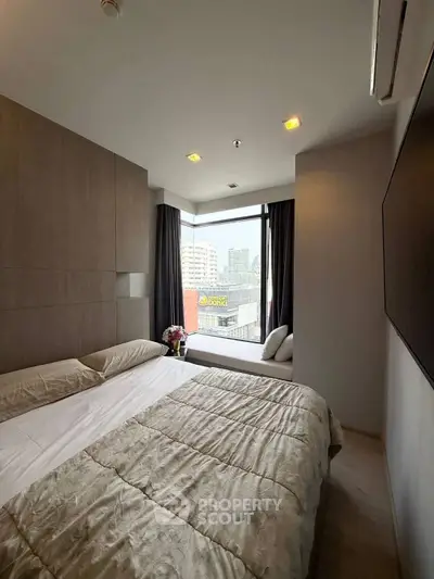 Modern bedroom with city view and cozy window seating area.