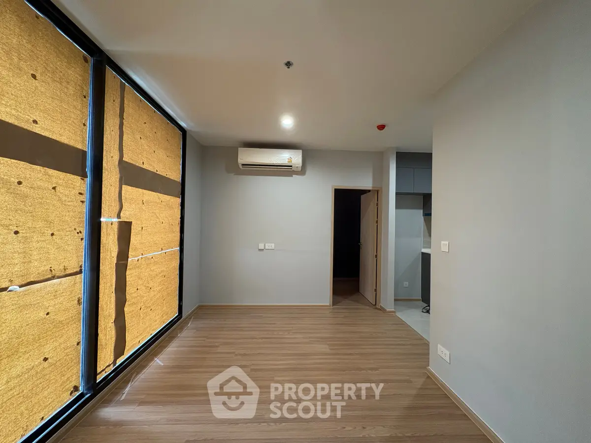 Spacious unfurnished room with wooden flooring and large windows, perfect for customization.