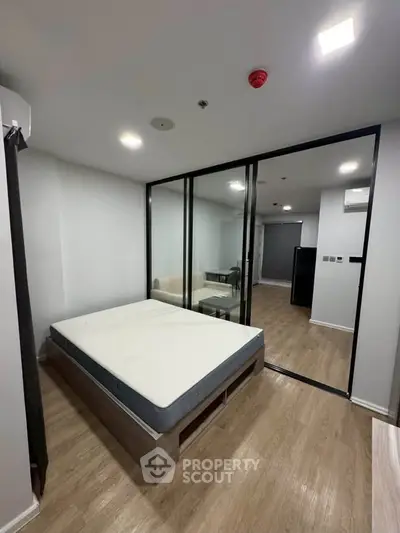 Modern bedroom with glass partition and wooden flooring in a stylish apartment.