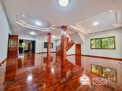 Spacious open-plan living room with polished wooden floors and elegant staircase