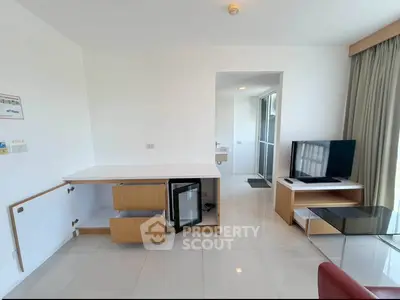 Modern living room with sleek furniture and natural light, featuring a compact kitchenette and TV area.