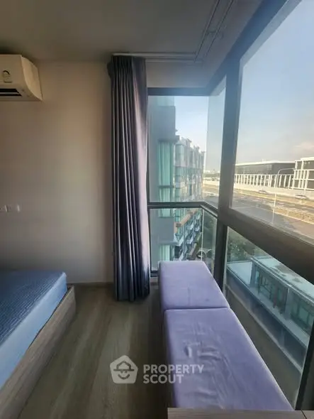 Modern bedroom with large windows offering stunning city views and natural light.