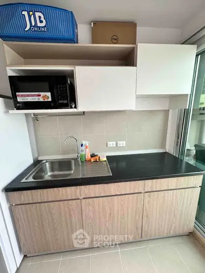 Modern kitchen with sleek cabinetry and built-in microwave, featuring a compact design and efficient layout.