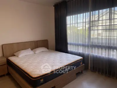 Spacious bedroom with large window and modern furnishings in a cozy apartment.