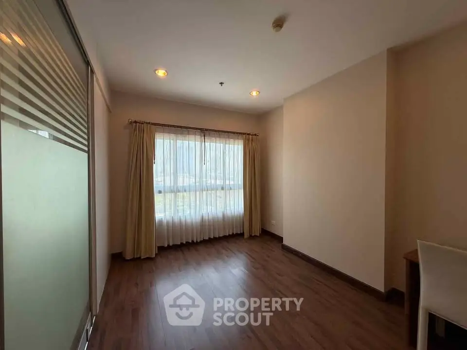 Spacious room with wooden flooring and large window for natural light