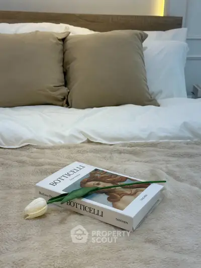 Cozy bedroom with plush bedding and elegant decor featuring a Botticelli art book.