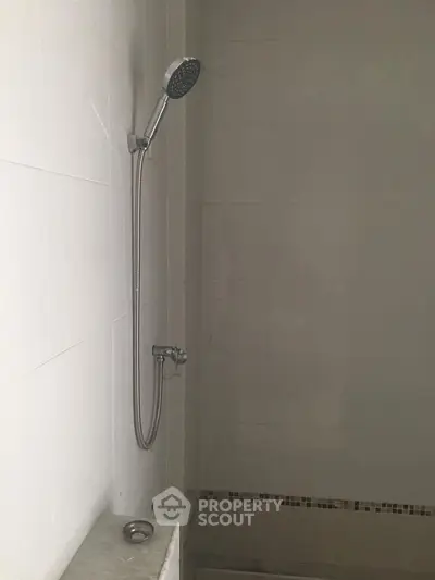 Minimalist bathroom with modern shower fixture and neutral tiles.