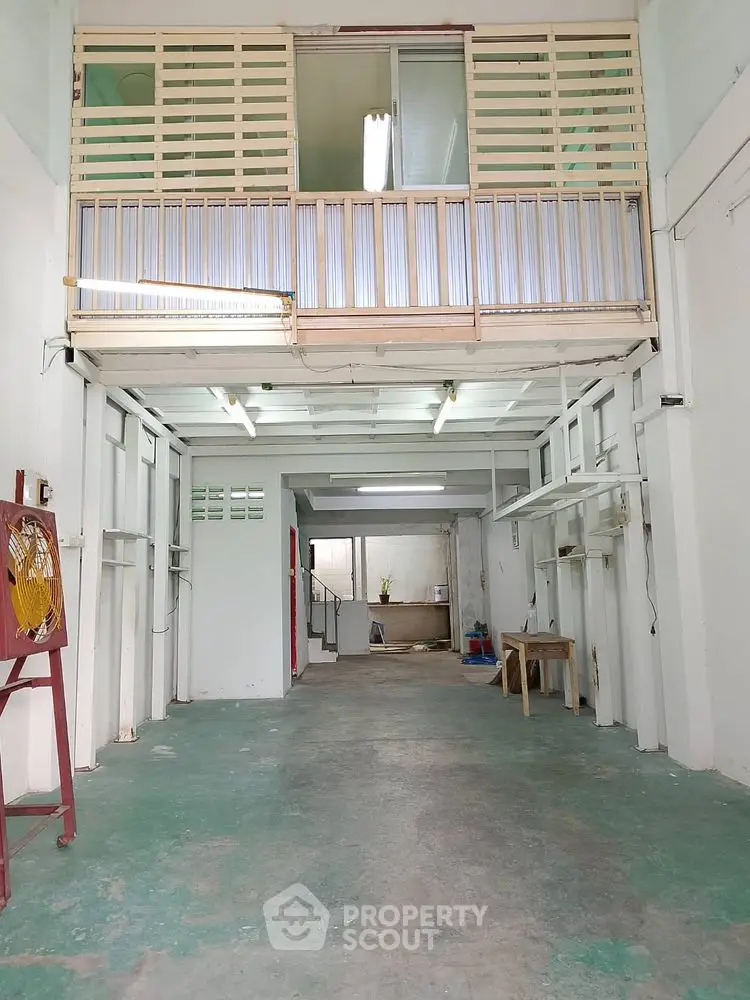 Spacious industrial-style interior with high ceilings and mezzanine level, ideal for creative workspace or studio.