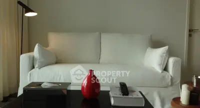 Modern living room with white sofa, red vase, and sleek decor