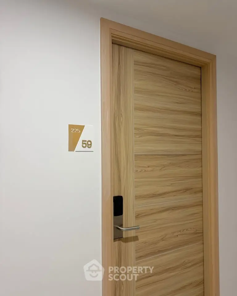 Modern apartment door with sleek wooden finish and room number signage.