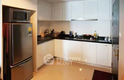 Modern kitchen with sleek white cabinets and stainless steel appliances in a cozy apartment.