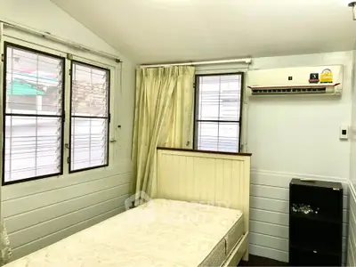 Cozy bedroom with air conditioning and natural light from two windows, perfect for relaxation.