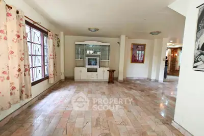 Spacious living room with large windows and elegant tiled flooring, perfect for family gatherings.