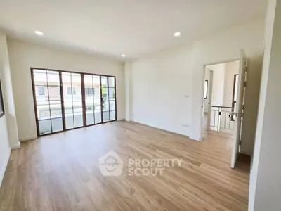 Spacious empty living room with wooden flooring and large windows for natural light.