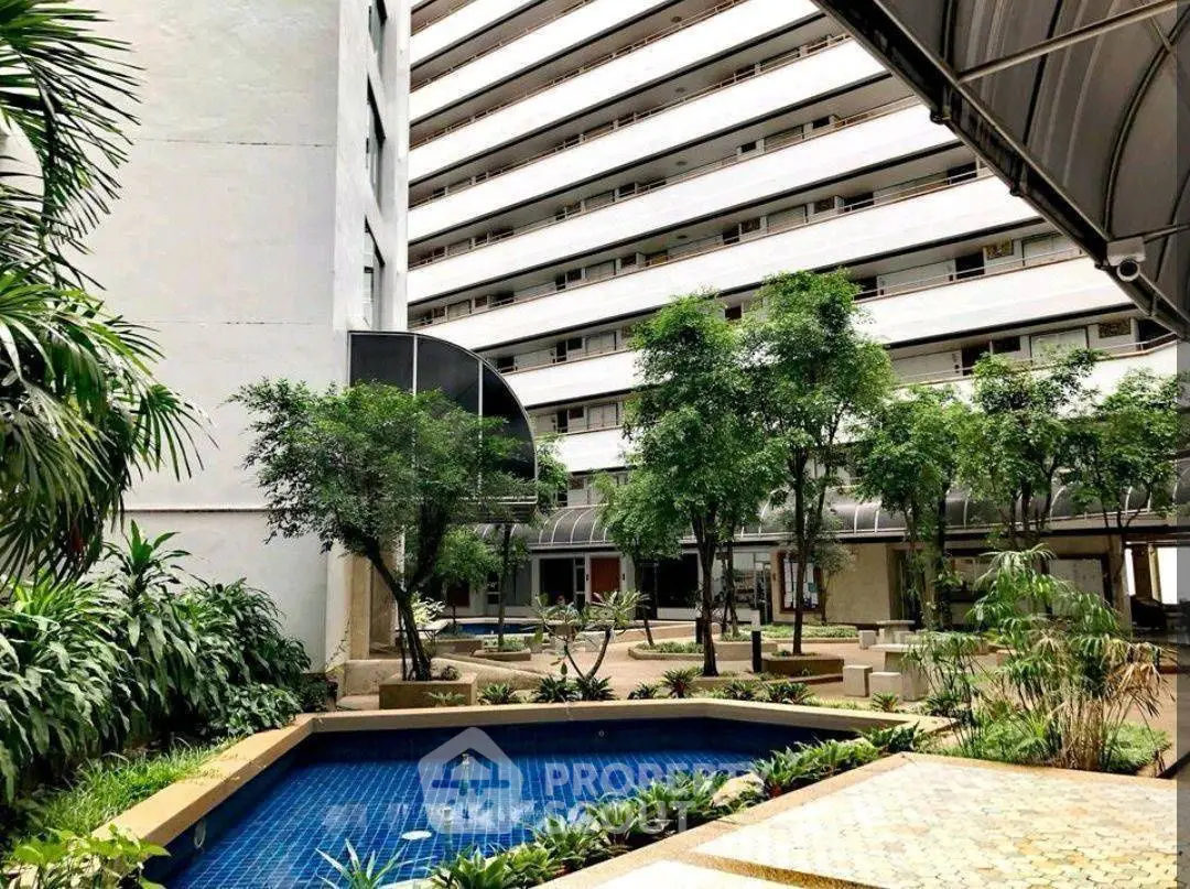 Luxurious residential building with lush garden and serene pool area.