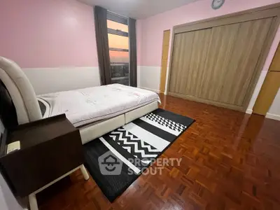 Spacious bedroom with wooden flooring and large window offering sunset views