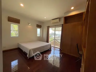 Spacious bedroom with balcony access and wooden flooring in modern home