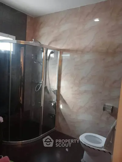 Modern bathroom with glass shower enclosure and tiled walls.