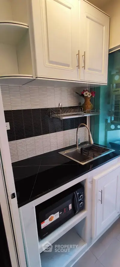 Compact modern kitchen with sleek black countertop and built-in microwave