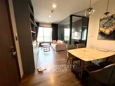 Modern open-layout living room with dining area and kitchen, featuring elegant decor and natural light.