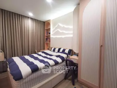 Cozy bedroom with modern design, featuring striped bedding and ambient lighting.