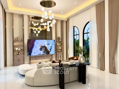 Luxurious living room with elegant decor, high ceilings, and modern lighting, featuring a large TV and stylish furniture.