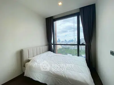Modern bedroom with large window offering stunning city view, featuring a cozy bed and elegant curtains.