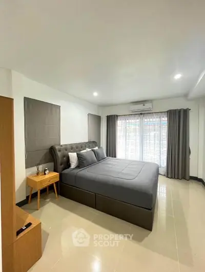Spacious modern bedroom with elegant decor and large windows for natural light.