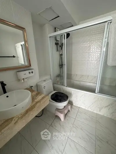 Modern bathroom with elegant marble flooring and stylish fixtures, featuring a glass-enclosed bathtub and sleek vanity.