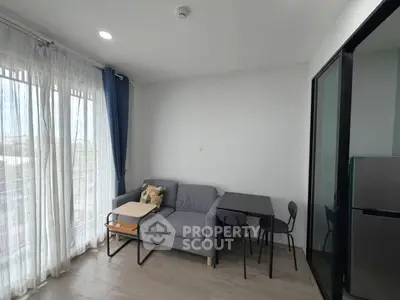 Modern living room with natural light, cozy sofa, and dining area in a stylish apartment.