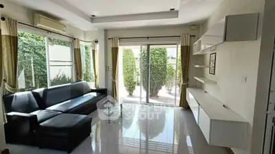 Spacious modern living room with large windows and garden view, featuring sleek furniture and elegant decor.