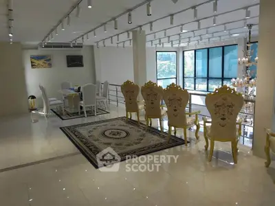 Luxurious open-plan living area with elegant dining set and chandelier, featuring large windows and modern decor.