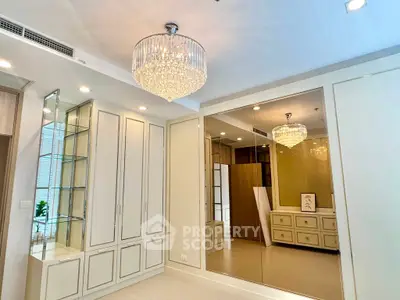 Luxurious bedroom with elegant chandelier and mirrored wardrobe in modern apartment.