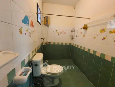 Charming bathroom with playful wall decals and green tile accents.