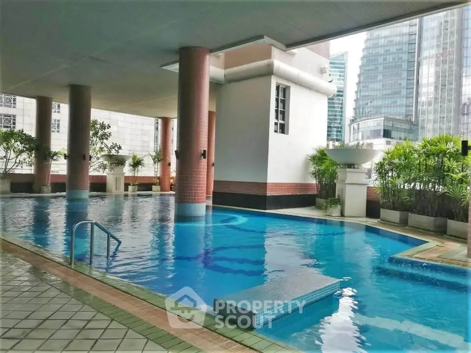Luxurious condominium pool area with modern architecture and city views, perfect for relaxation and leisure.