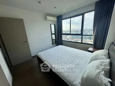 Modern bedroom with large window offering city view, featuring a comfortable bed and air conditioning.