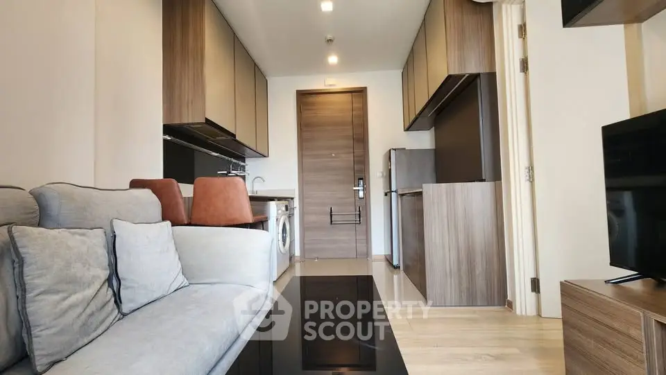 Modern apartment interior with sleek kitchen and cozy living area, featuring stylish furniture and appliances.