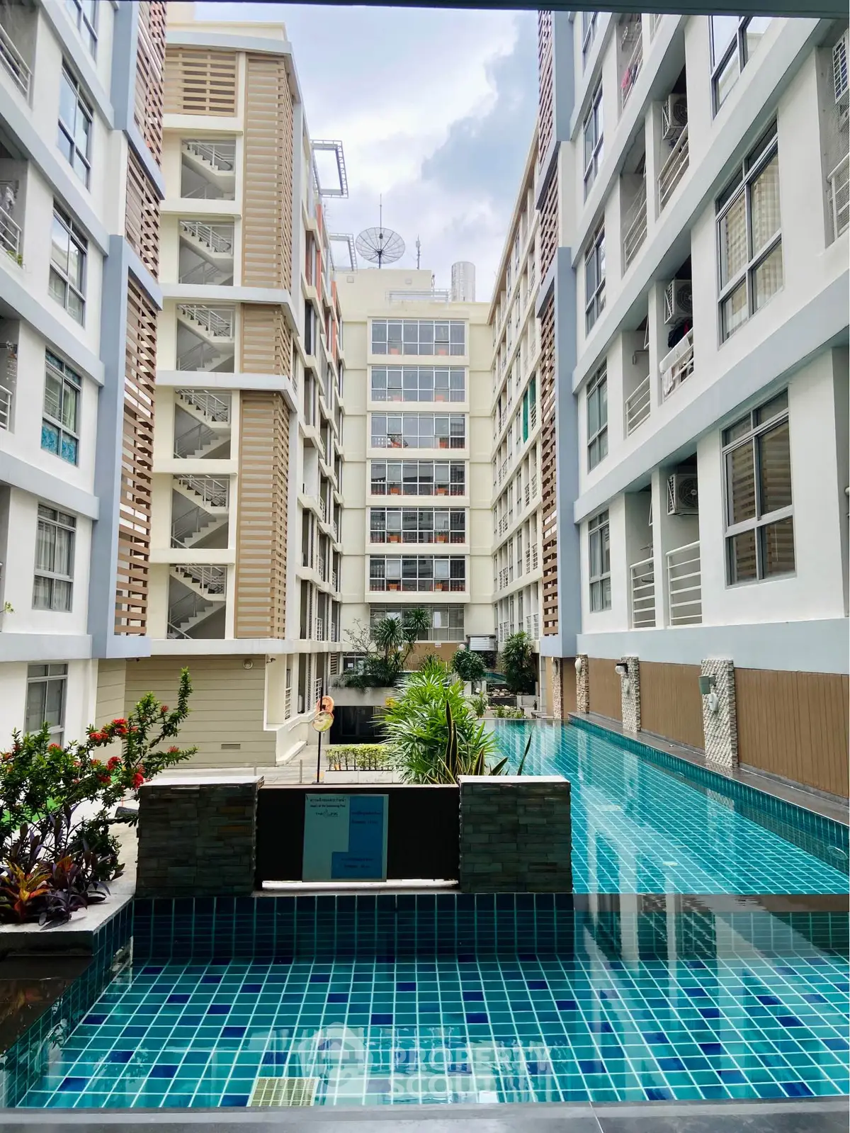 Modern apartment complex with a stunning pool view and lush greenery.