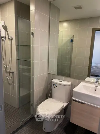 Modern bathroom with glass shower and sleek fixtures in contemporary apartment.