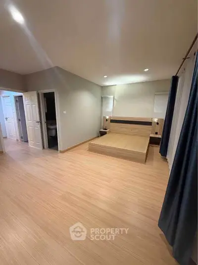 Spacious bedroom with modern wooden flooring and minimalist design