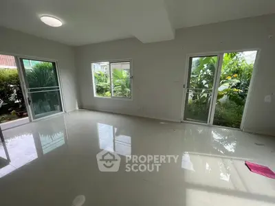 Spacious living room with large windows and garden view, perfect for natural light lovers.