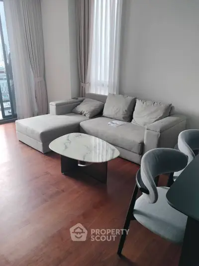 Modern living room with stylish gray sofa and marble coffee table on wooden floor