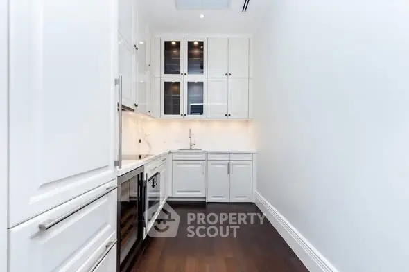 Sleek modern kitchen with white cabinetry and dark wood flooring, perfect for culinary enthusiasts.