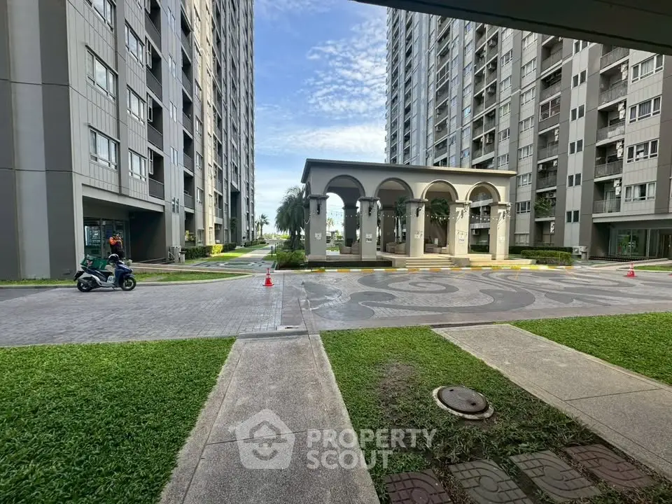 Modern residential complex with spacious courtyard and elegant archway entrance.